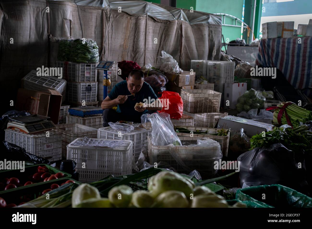 a vendor have lunch on his stall in a produce market. Stock Photo