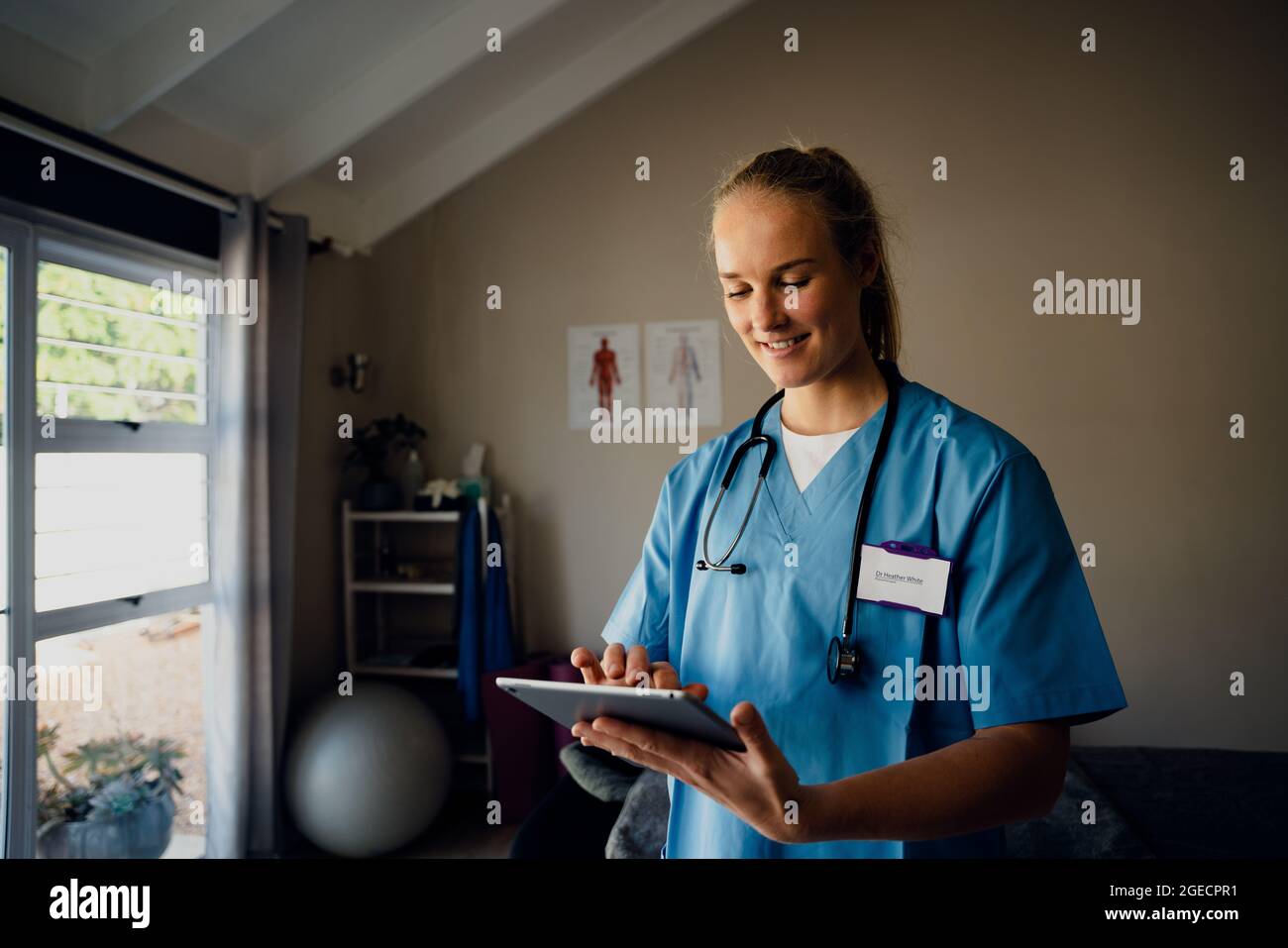 Caucasian female nurse preparing for online consultation with patient over video call standing in clinic Stock Photo