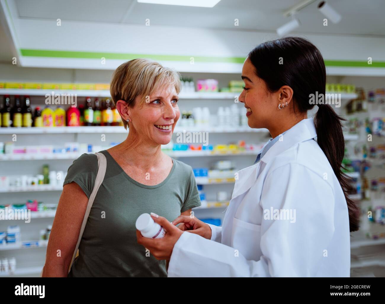 Middle-aged mother getting assistant by mixed race female intern helping prescribe medication  Stock Photo