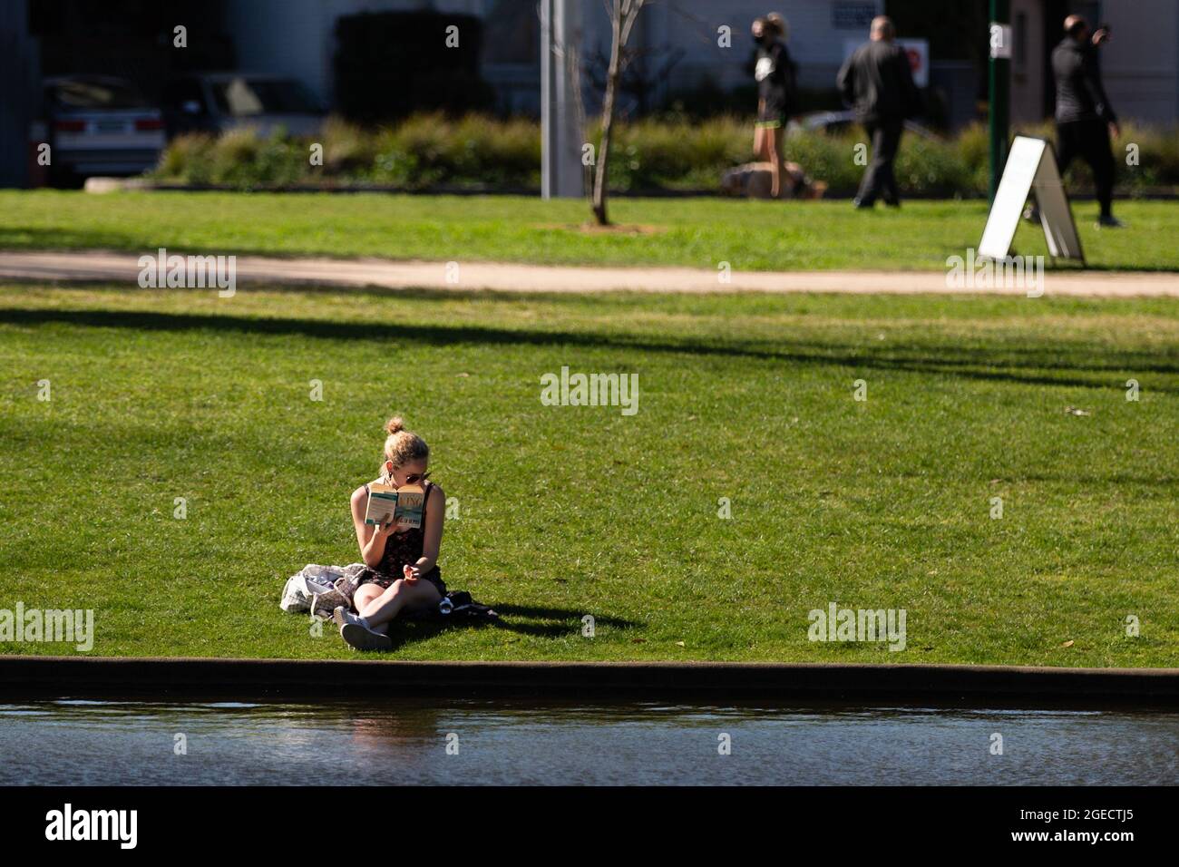Melbourne, Australia, 8 September, 2020. A woman is seen reading a book by a lake during COVID-19 in Melbourne, Australia. Melbournians enjoy the sunshine as the State of Victoria plunges deeper into recession with a depression looking more likely, trust in the Andrews Government is wavering amid the release of their Road Map out of the worlds most draconian and longest lasting restrictions. The medical community has hit out against Premier Daniel Andrews suggesting his tunnel vision approach is causing more damage than the disease. Victoria recorded another 41 cases of Coronavirus over the p Stock Photo
