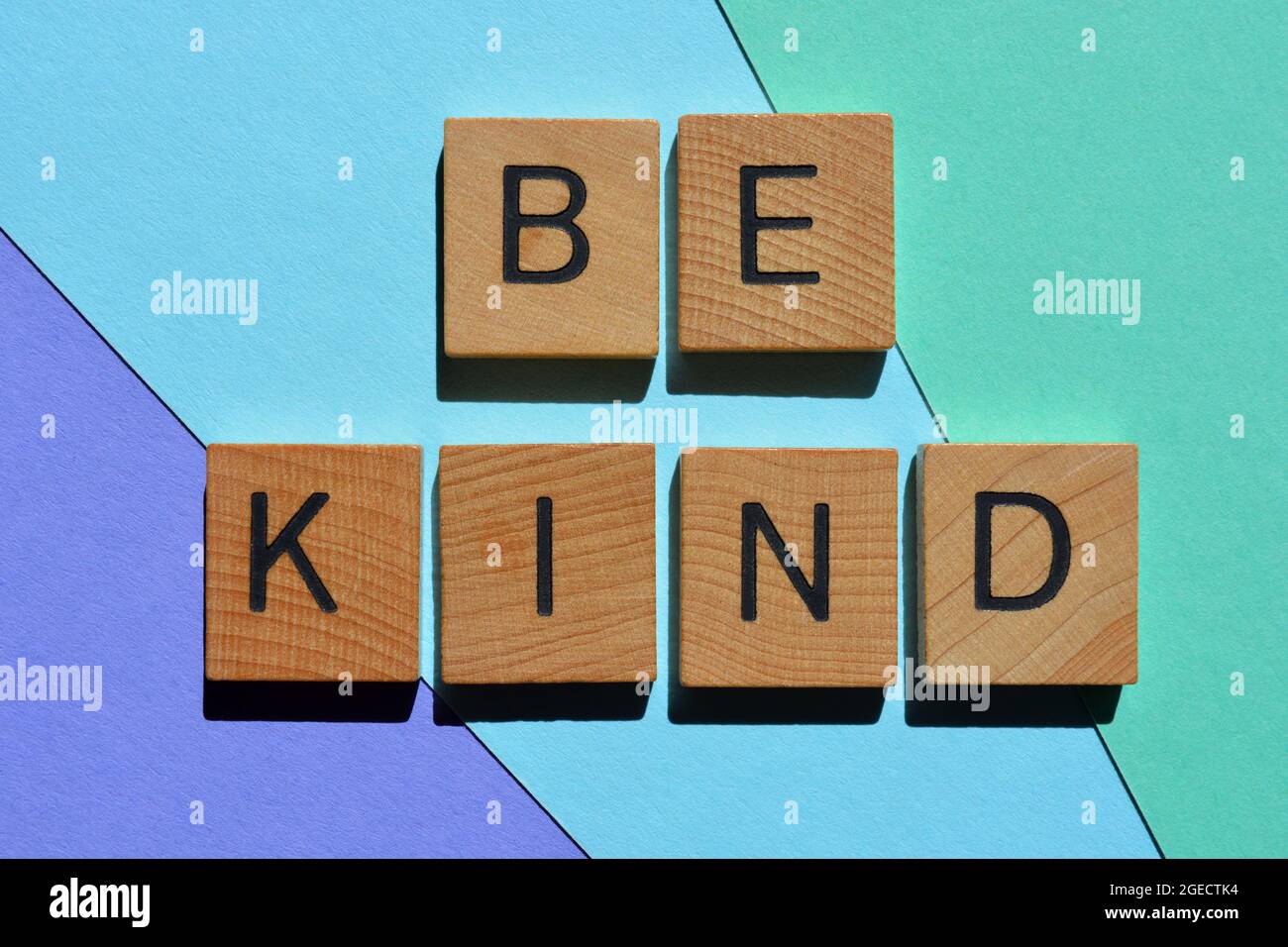 Be Kind, positive words in wooden alphabet letters isolated on colourful background Stock Photo