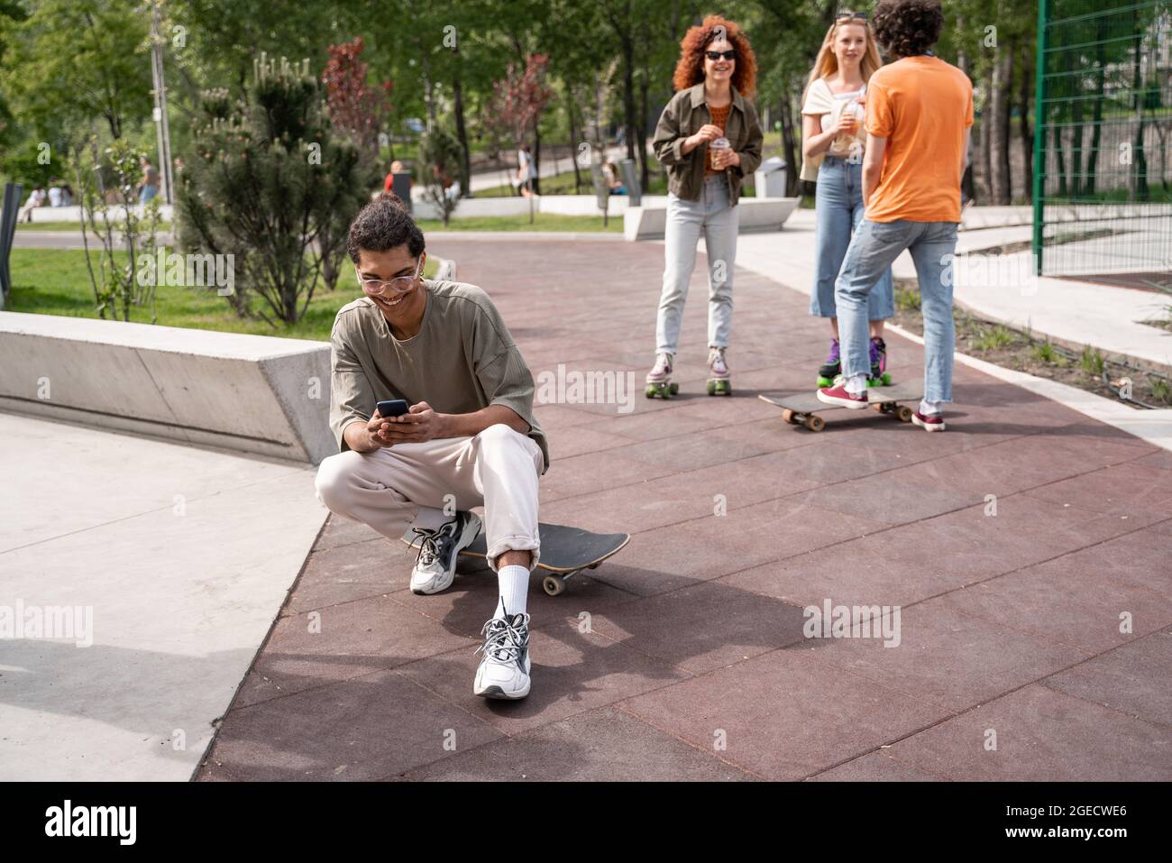 cheerful african amercian man chatting on mobile phone near friends in skate park Stock Photo