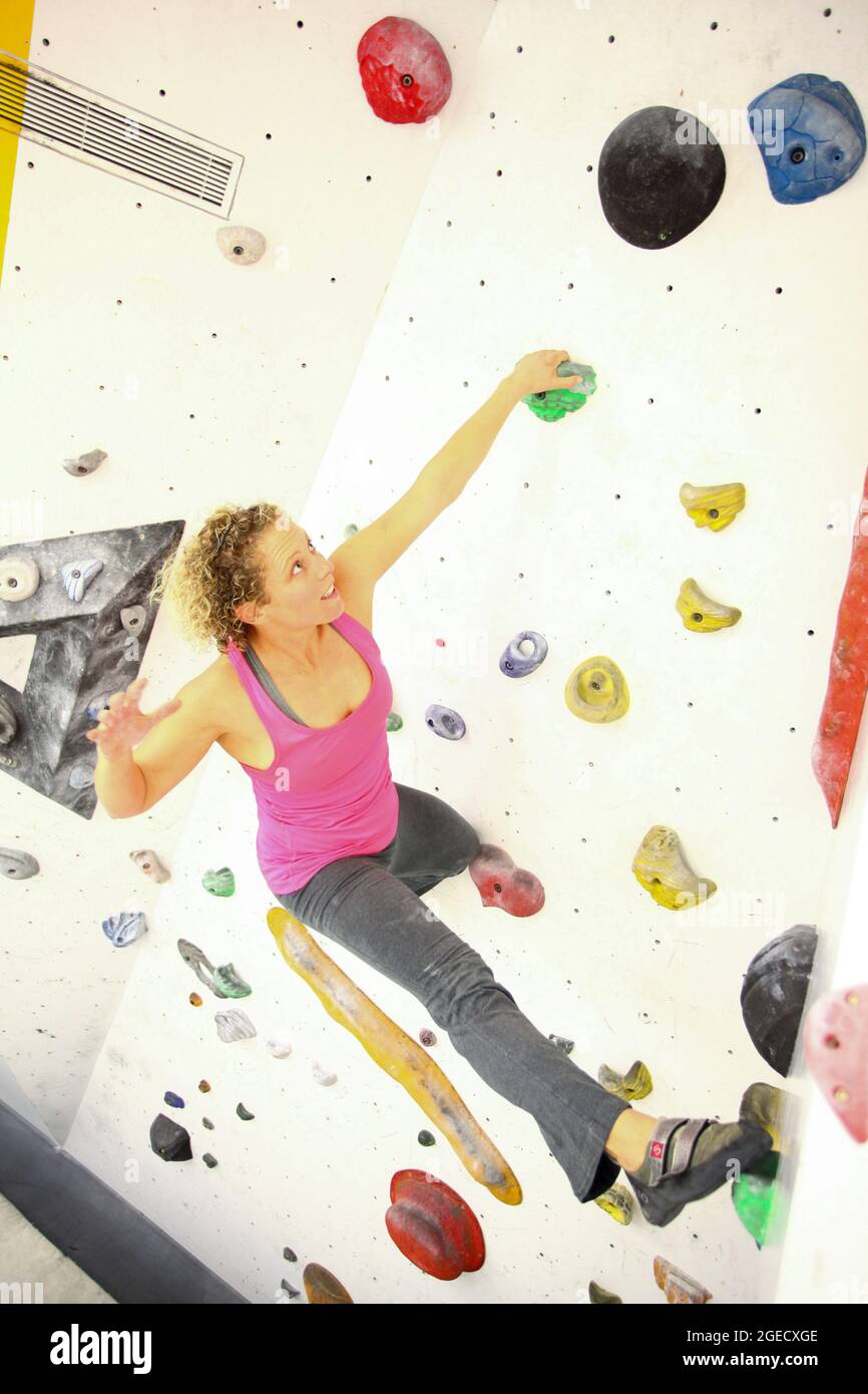 Young teen girl climbs up an artificial climbing wall Stock Photo