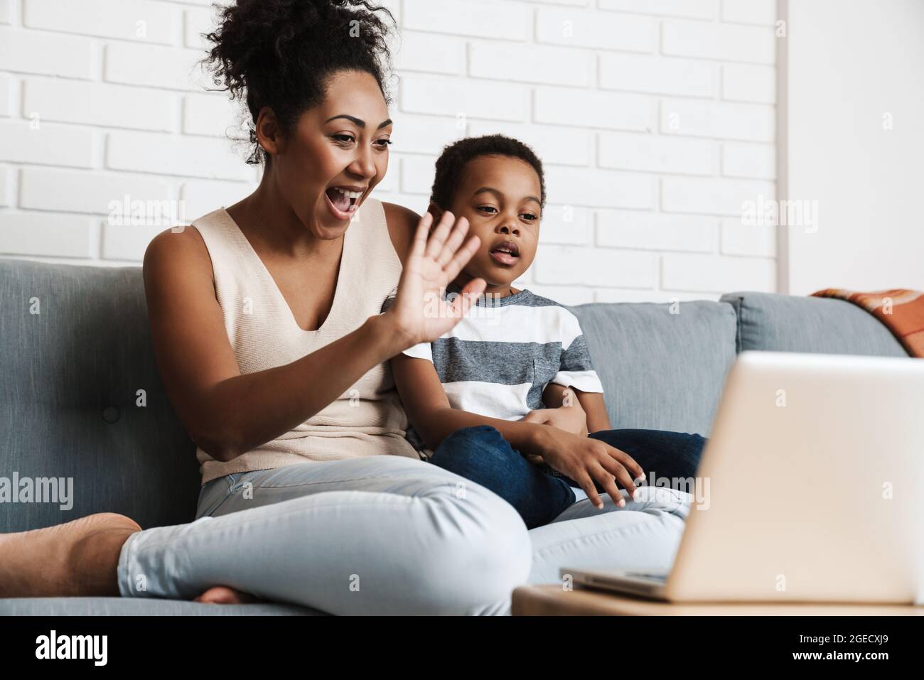 Black happy mother and son gesturing while using laptop at home Stock Photo