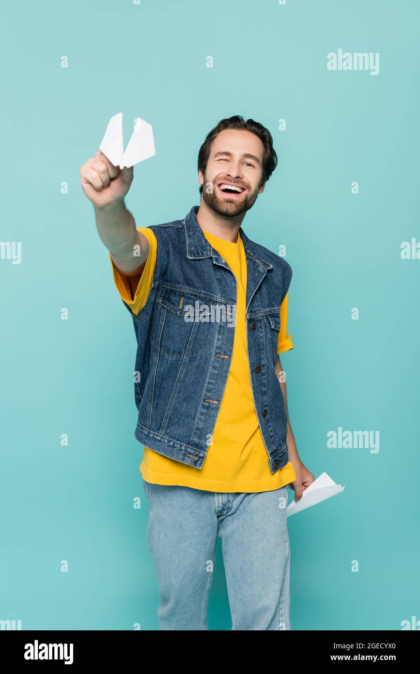 Smiling man holding paper planes isolated on blue Stock Photo