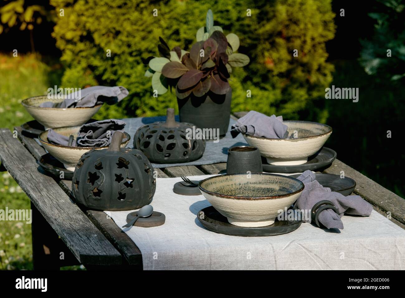 Rustic table setting outside in garden with empty craft ceramic tableware Stock Photo