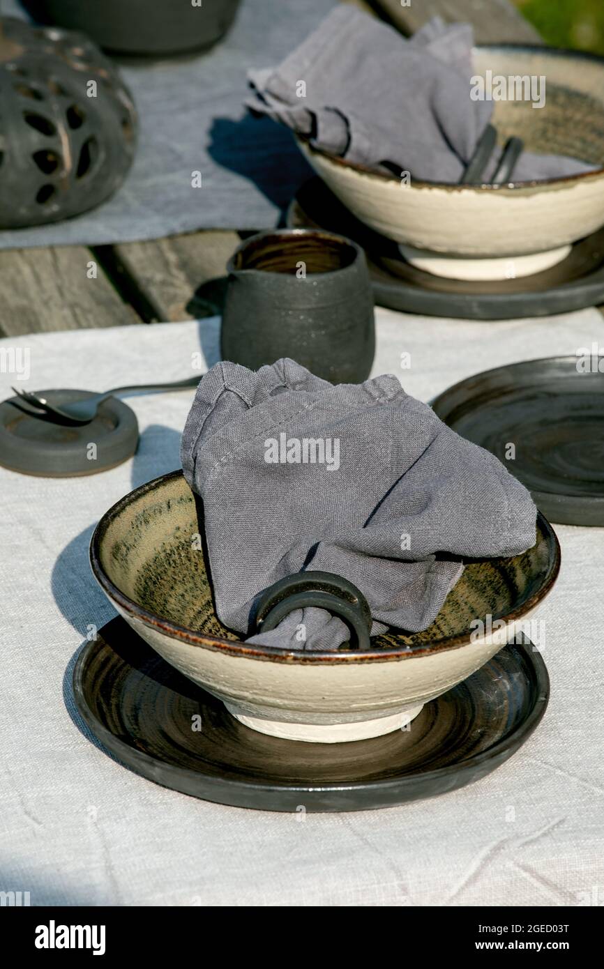 Rustic table setting outside in garden with empty craft ceramic tableware Stock Photo