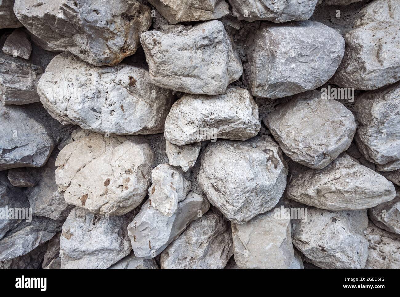 A close-up of a wall texture laid of stone boulders. Background pattern of grey color and different sizes and shapes. Backdrops, constructions, old ru Stock Photo