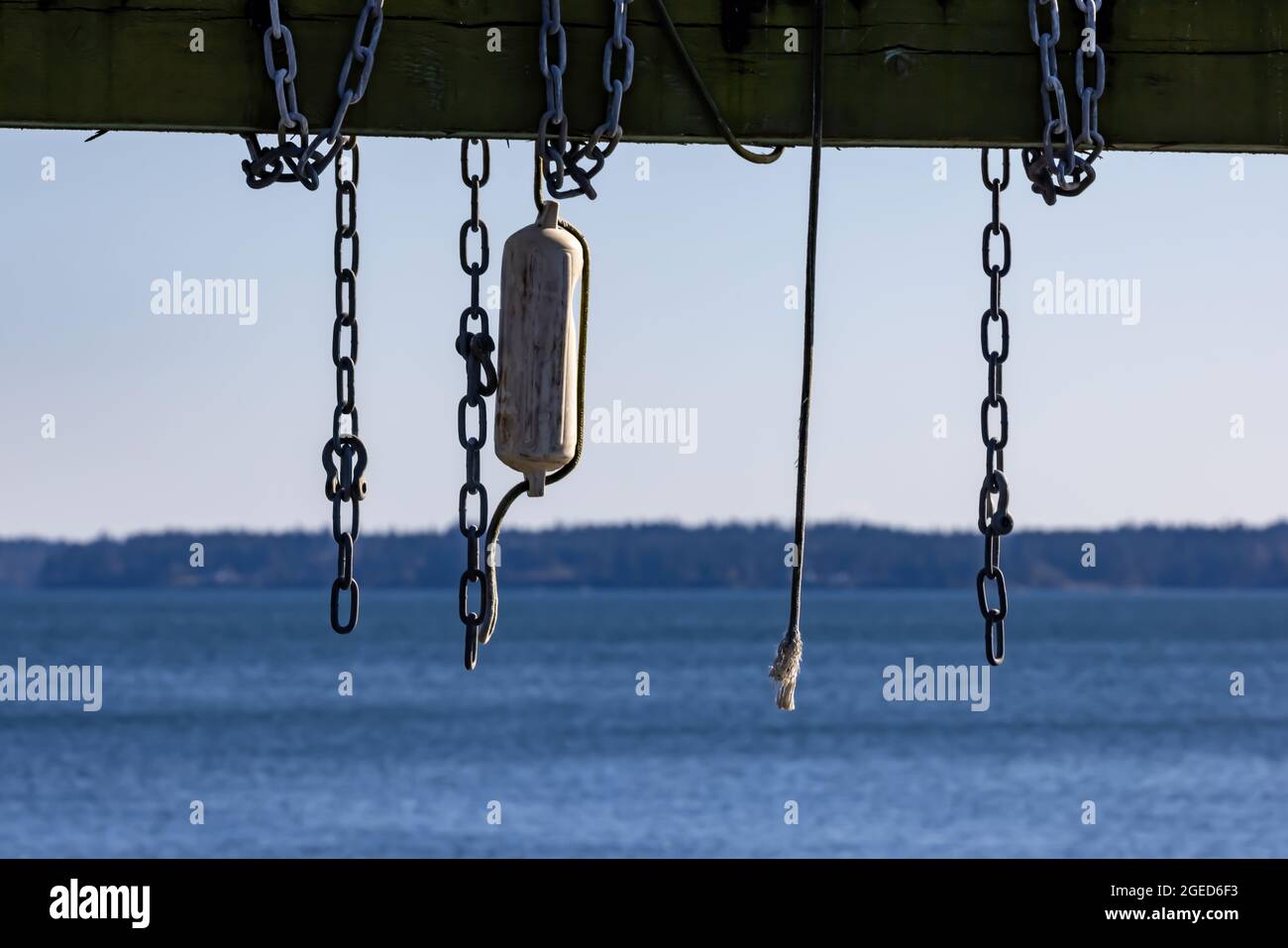 ropes chains and bouys hanging on a wooden beam out on a boat