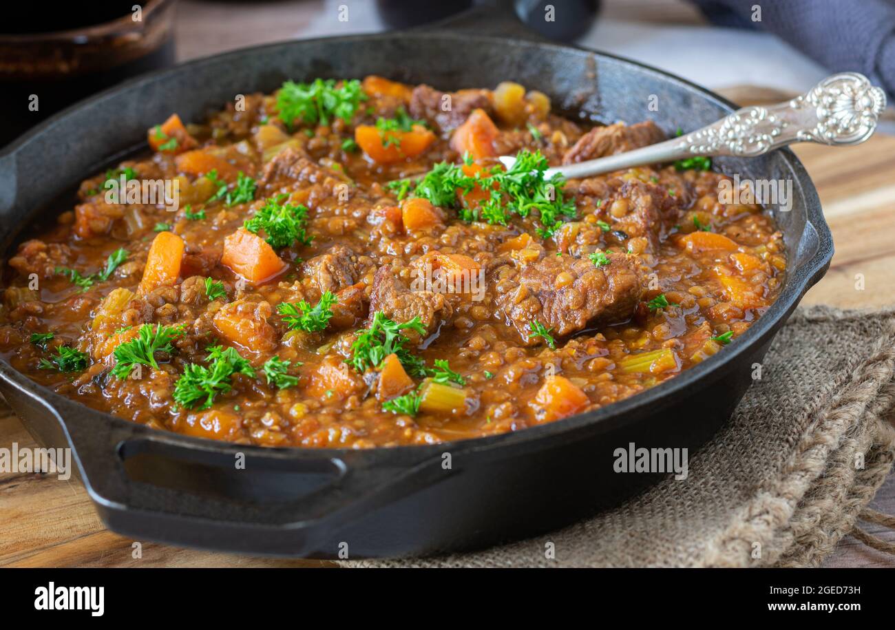 Brown beef stew with lentils and vegtables in a cast iron pan Stock