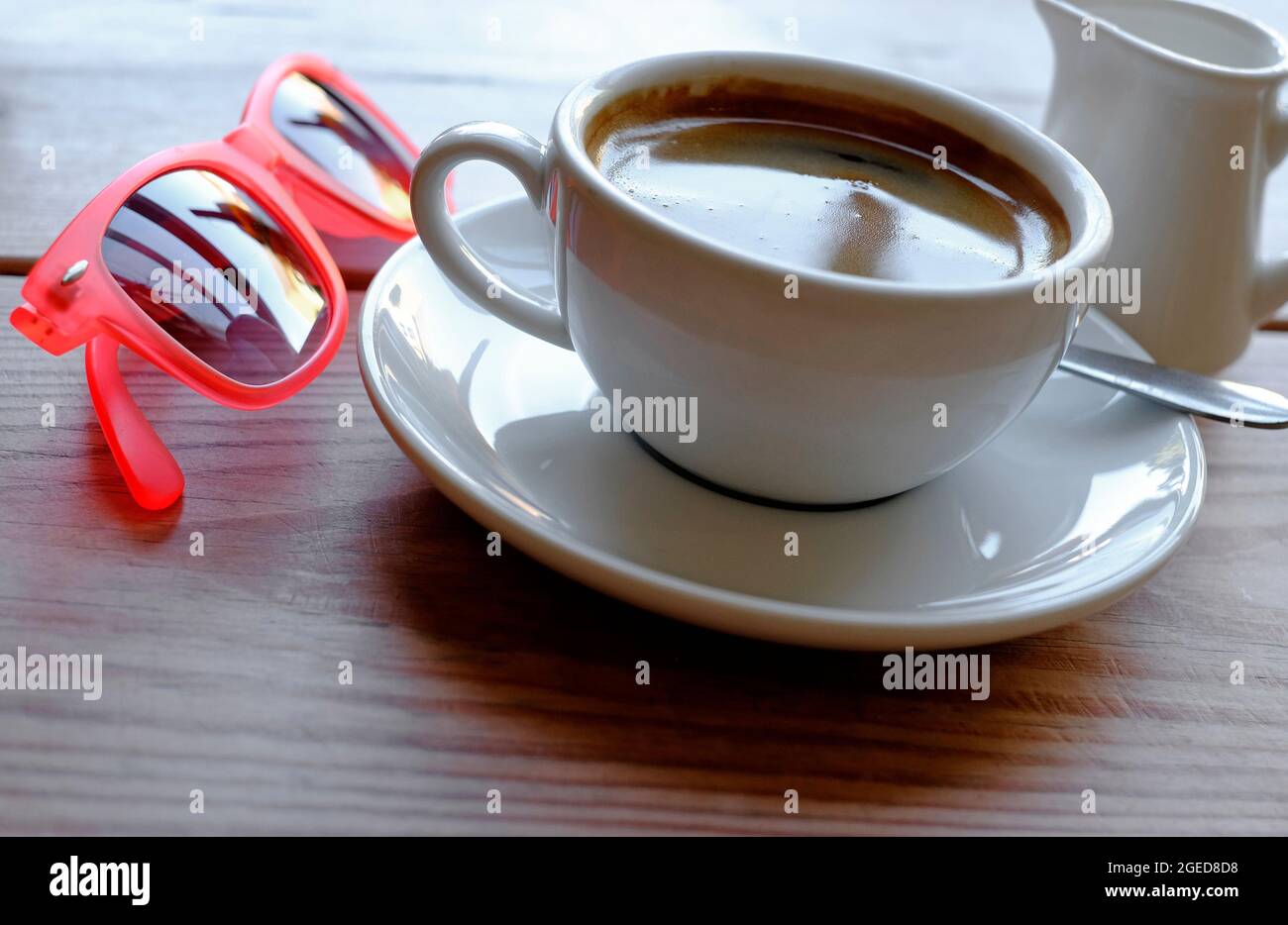 cup of americano coffee on cafe table and red sunglasses Stock Photo