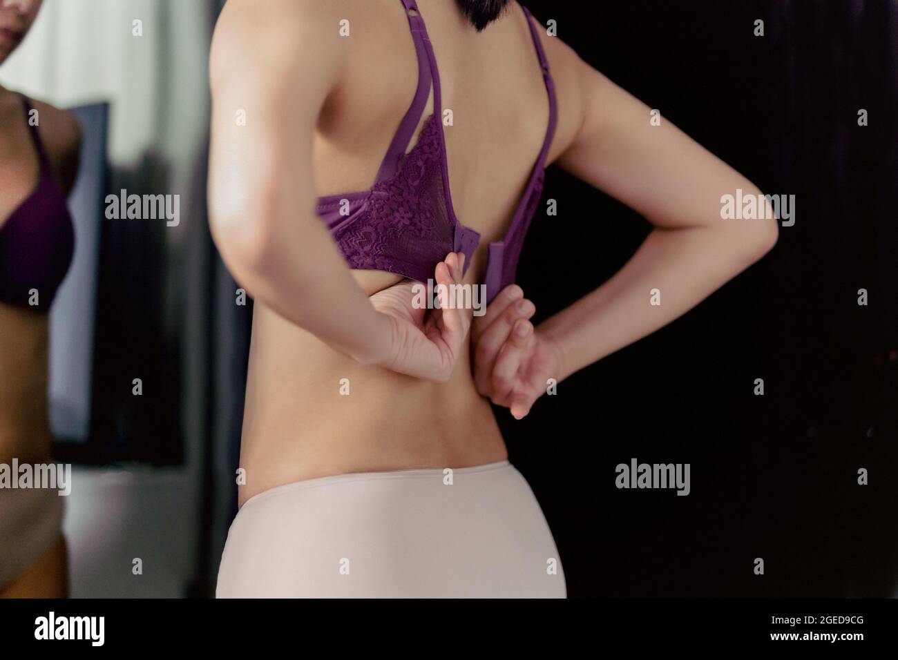 https://c8.alamy.com/comp/2GED9CG/shot-in-low-light-woman-unhooking-her-bra-and-looking-in-the-mirror-indoors-2GED9CG.jpg