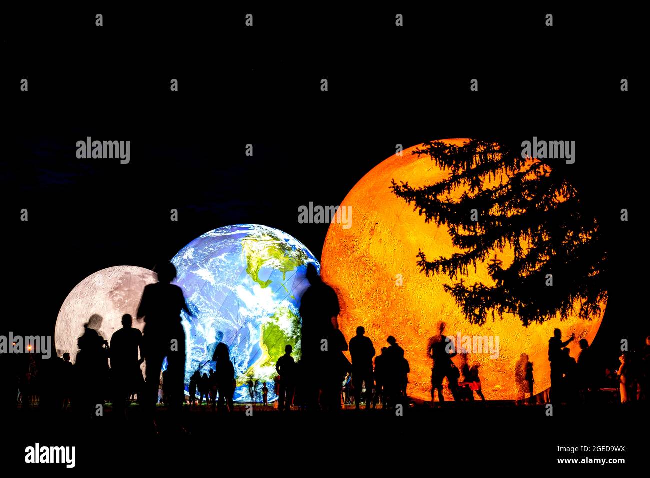 BRNO, Czech Republic - August, 14. 2020 Giant inflatable model of the planets Mars, Earth and Moon at night with silhouettes of people. Solar system Stock Photo