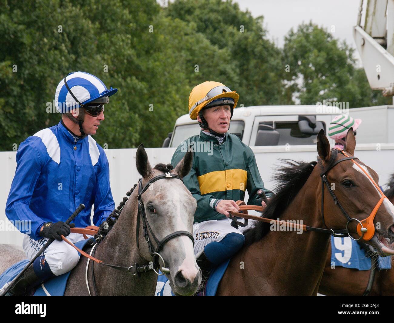 Jockeys Jim Crowley and Sam Hitchcott chat before the start of a race at York Racecourse. Stock Photo
