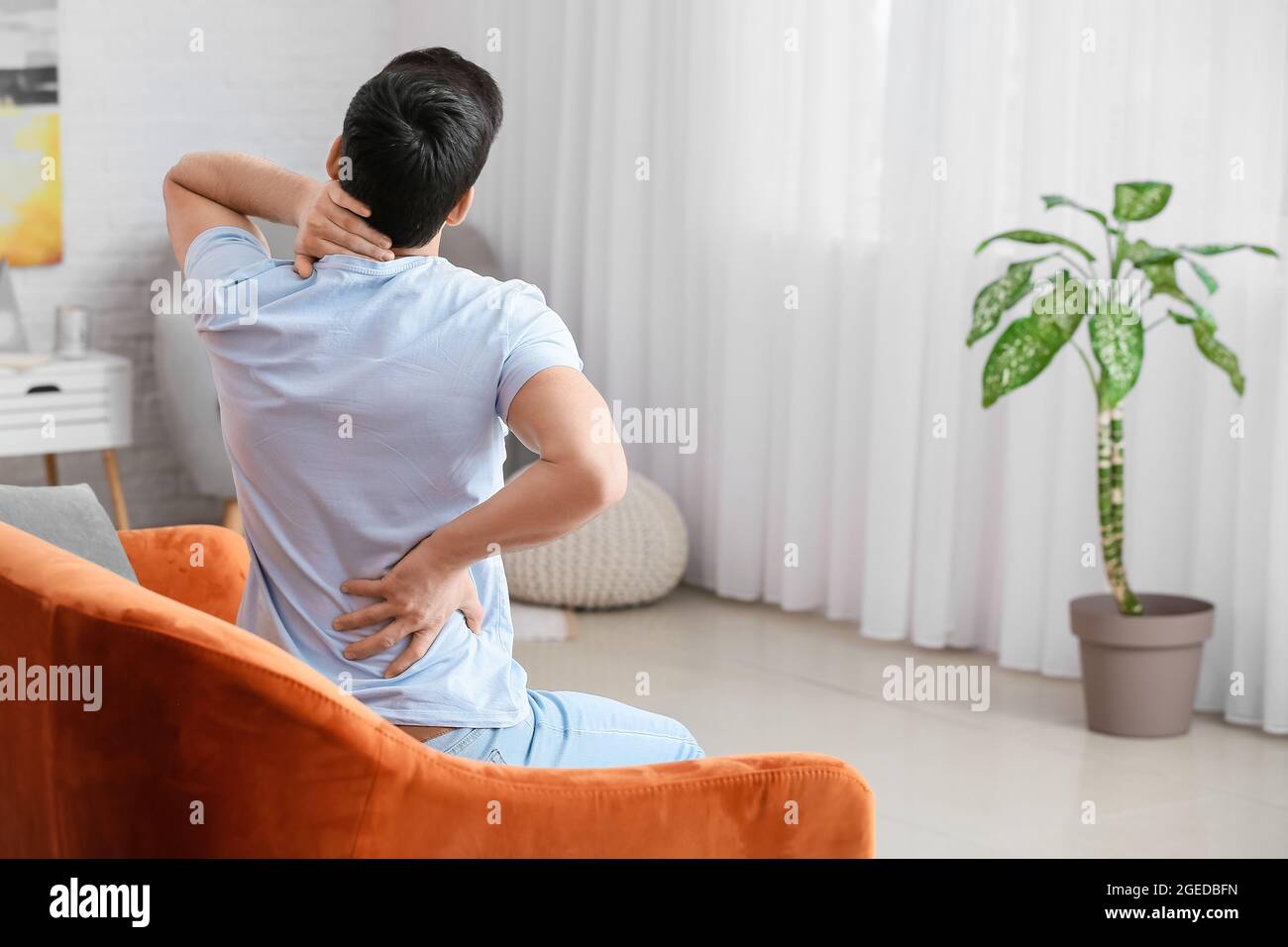 Young man suffering from back pain at home Stock Photo - Alamy