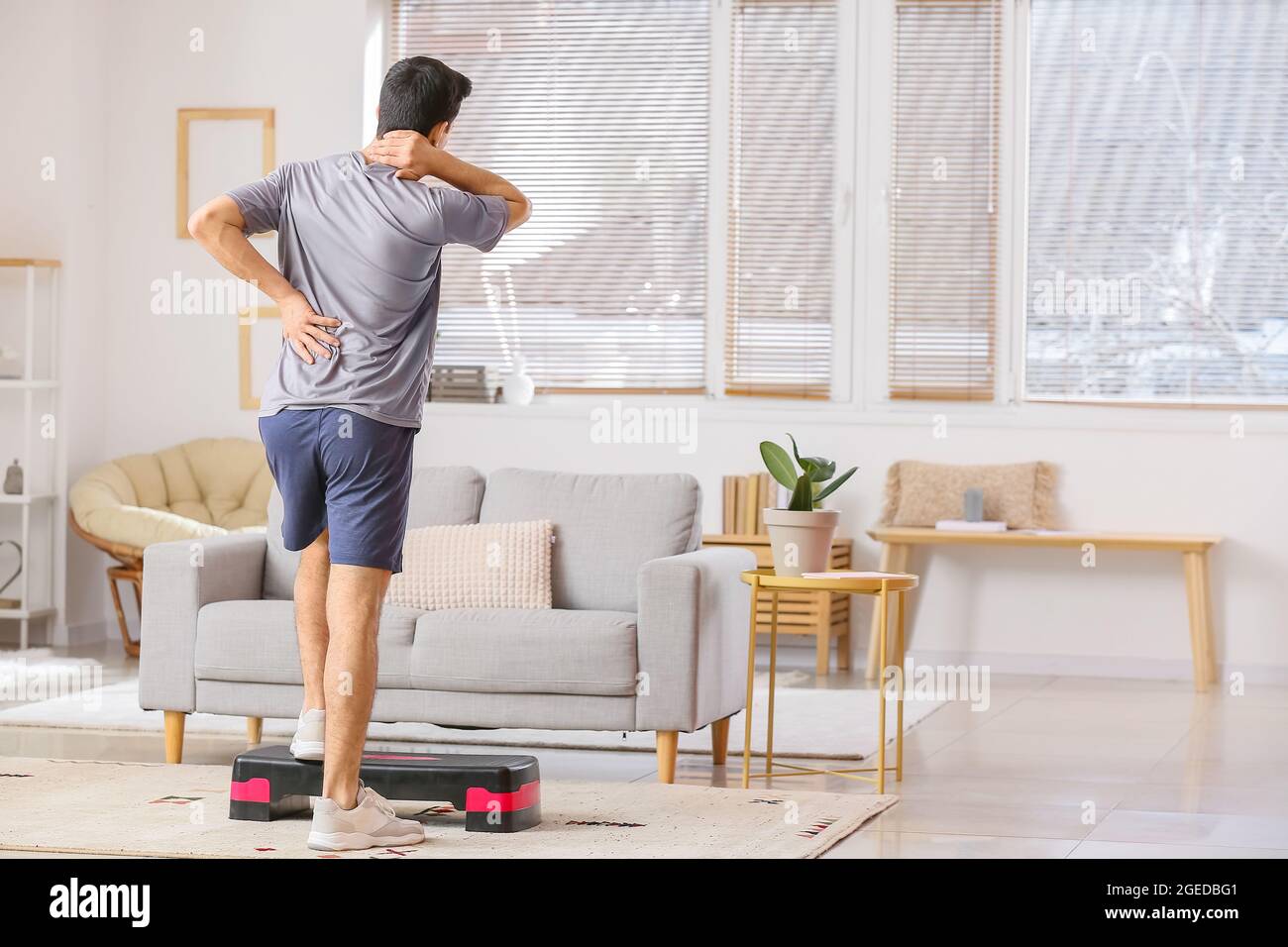 Young man with stepper suffering from back pain at home Stock Photo Alamy