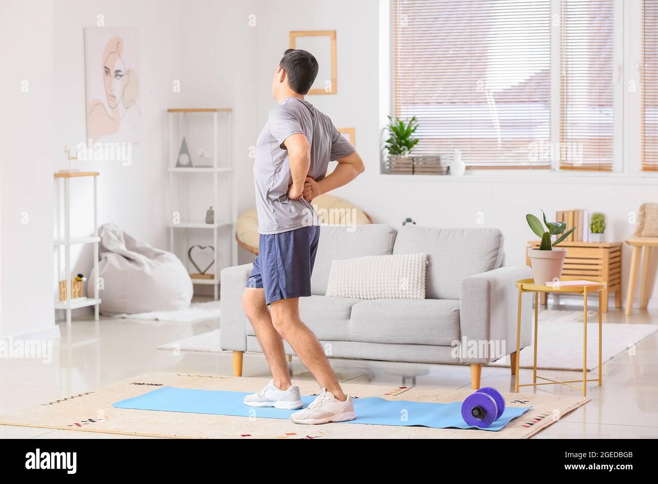 Young man suffering from back pain at home Stock Photo - Alamy