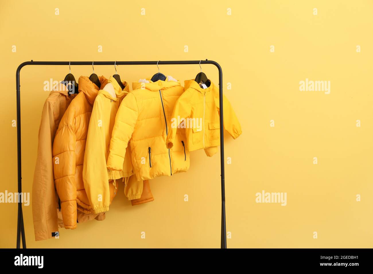 Rack with stylish clothes near color wall Stock Photo