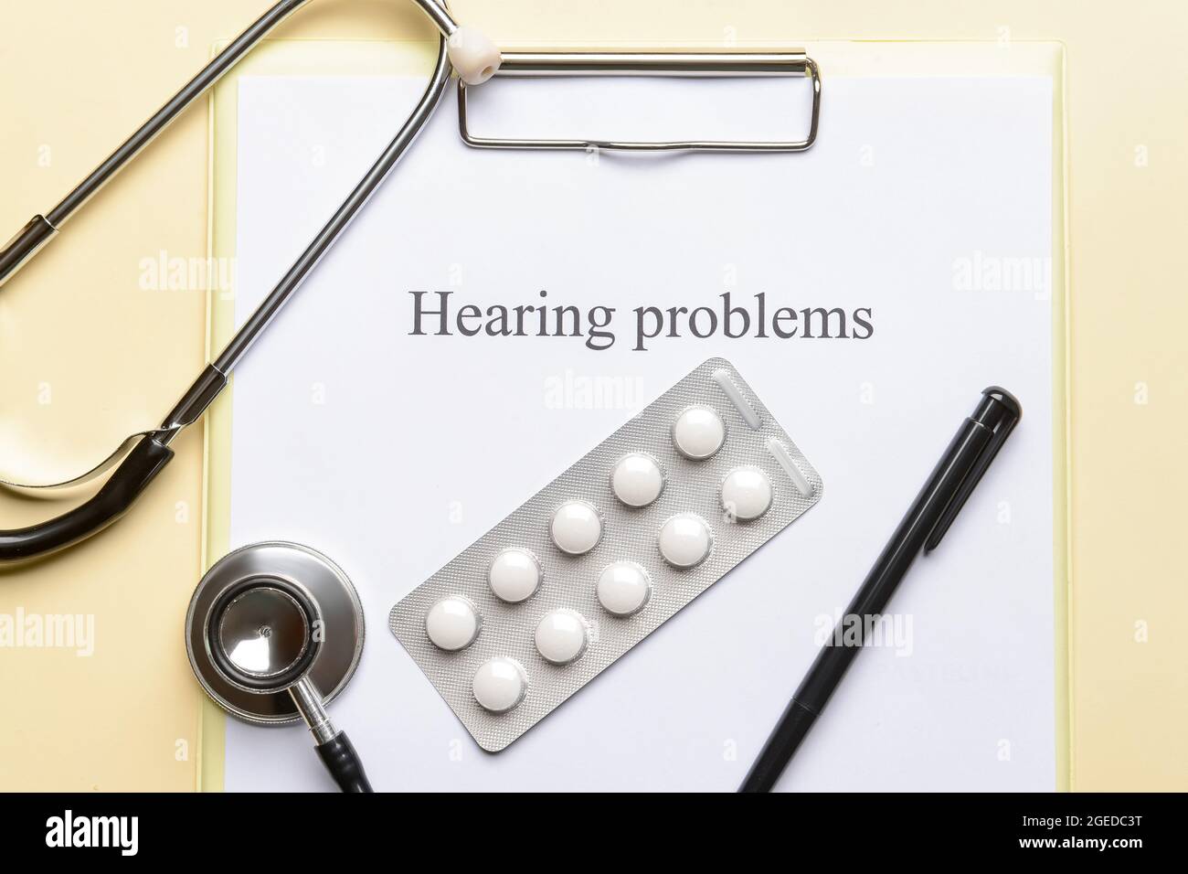 Clipboard with text HEARING PROBLEMS and pills on color background Stock Photo