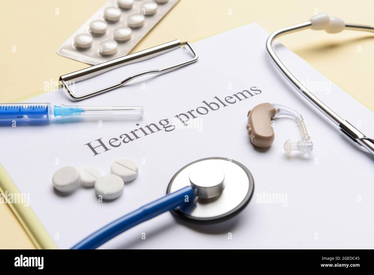 Clipboard with text HEARING PROBLEMS and pills on color background Stock Photo
