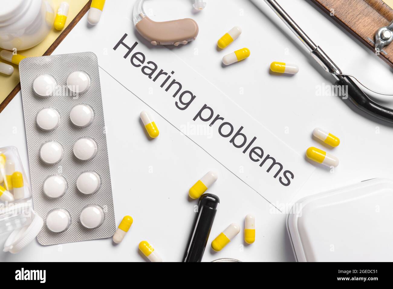 Clipboard with text HEARING PROBLEMS and pills on color background Stock Photo