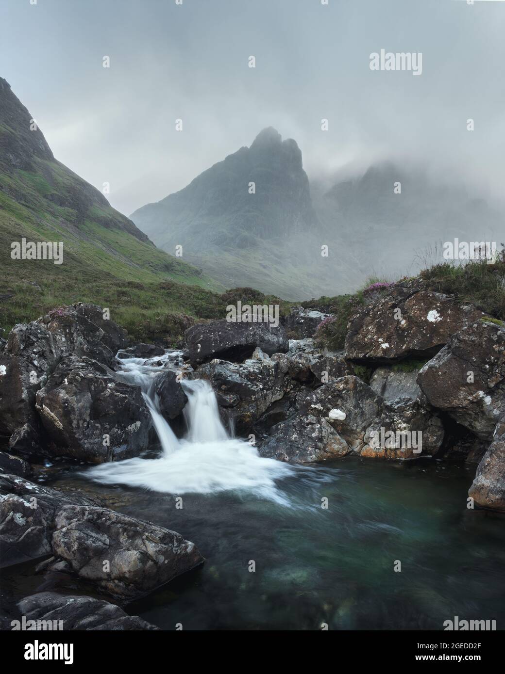 Morning view of river with waterfall and cloud covered mountain range