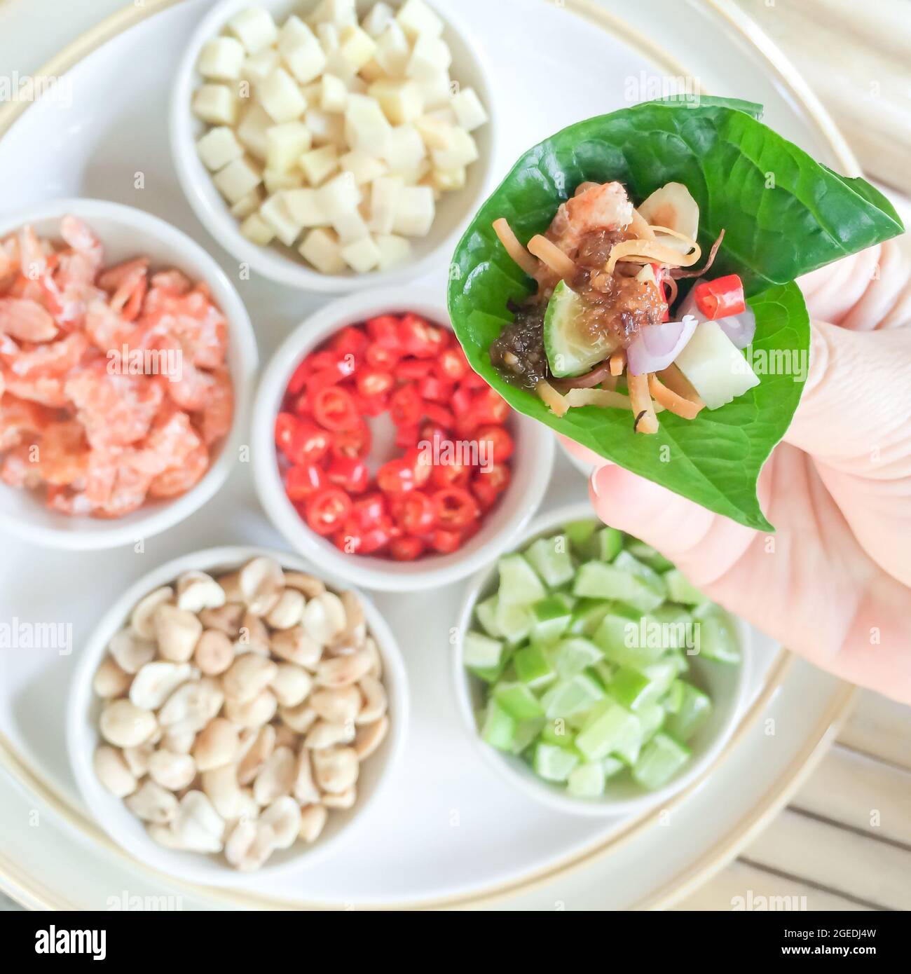 Closeup hand holding royal leaf wrap appetizer or Miang Kham