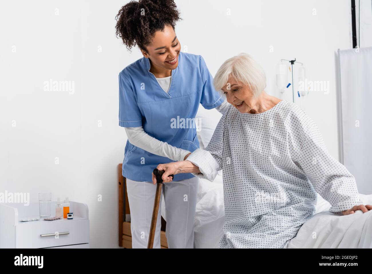 Smiling african american nurse helping patient with walking cane near