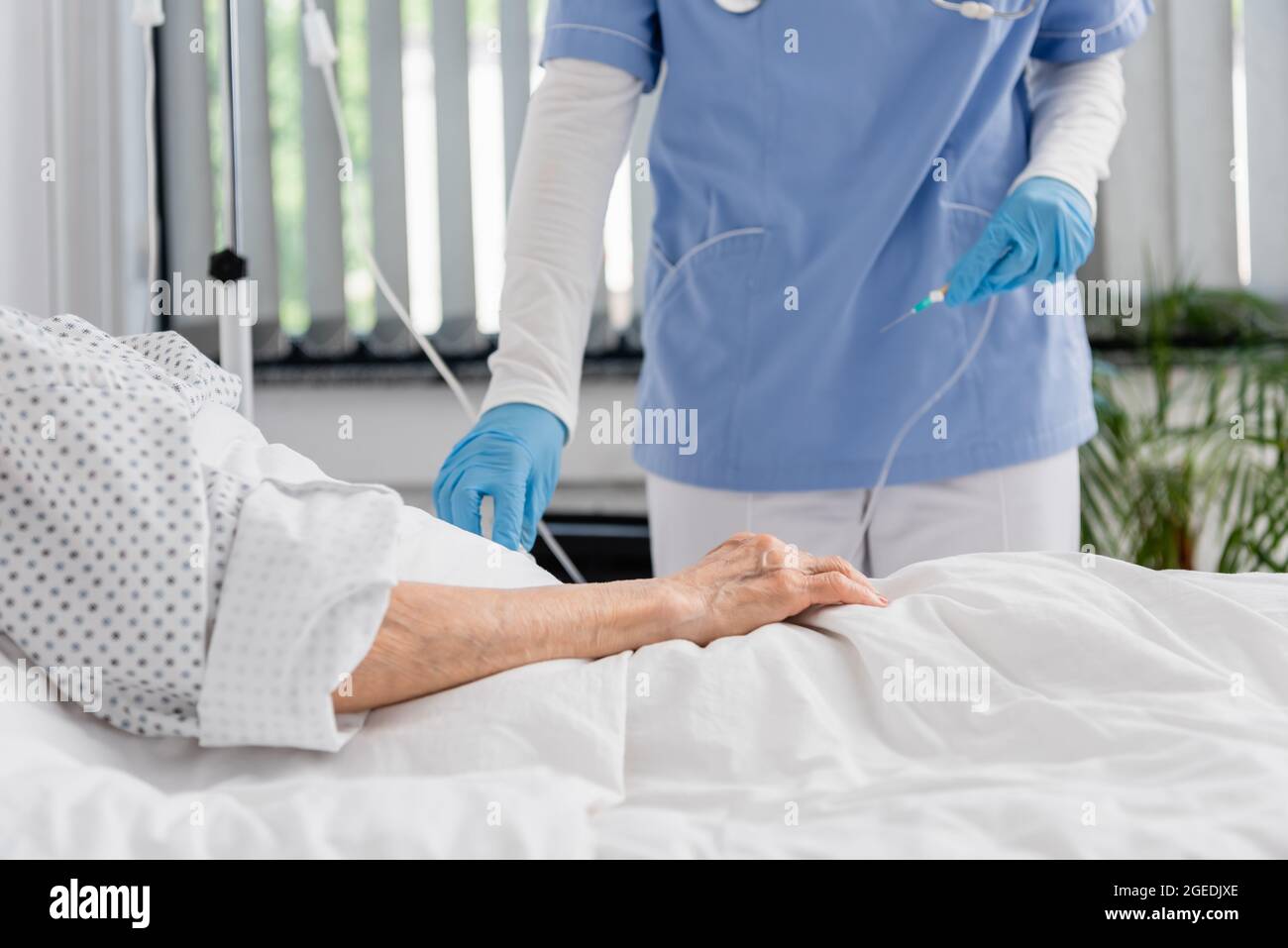 Cropped view of nurse holding catheter near senior woman on hospital
