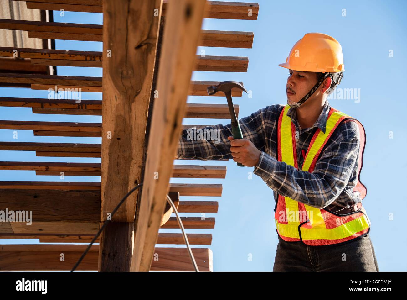 Asian roofer carpenter working on roof structure on construction site ...