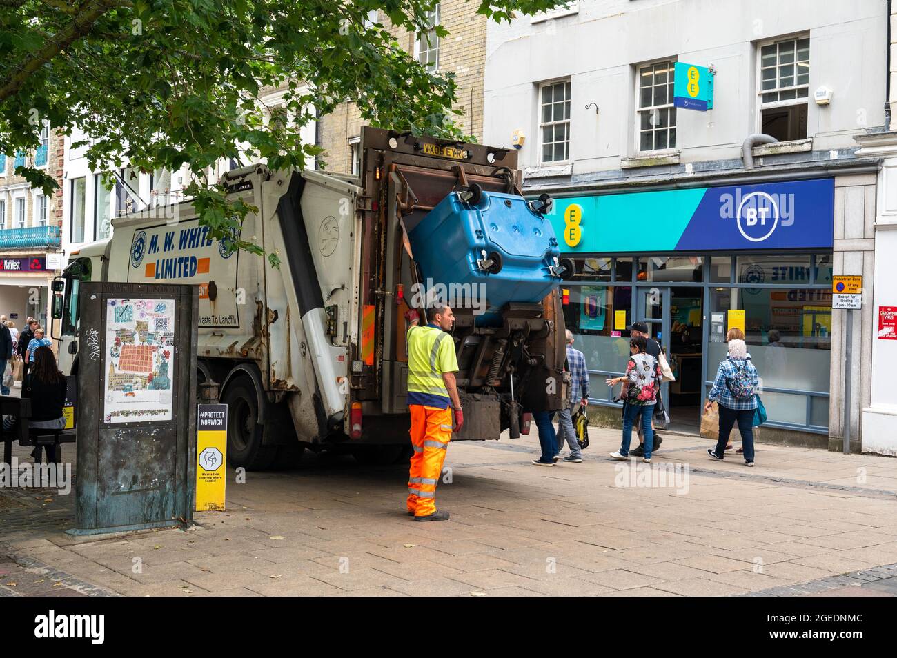 Dustman emptying a commercial blue bin in the centre of Norwich city on a busy day Stock Photo