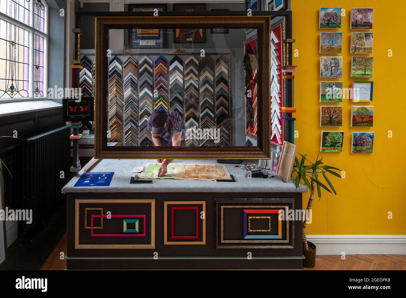 Inside a picture framing business with a person measuring up a map to be framed, West Yorkshire