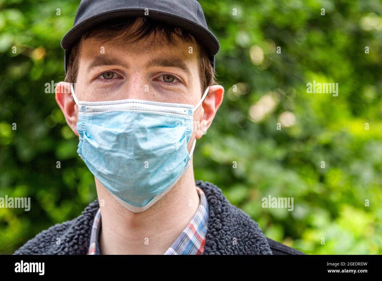 A young man wearing a face mask outdoors. Wearing a face covering as a measure to prevent the spread of the Covid 19 virus became the new normal. Stock Photo
