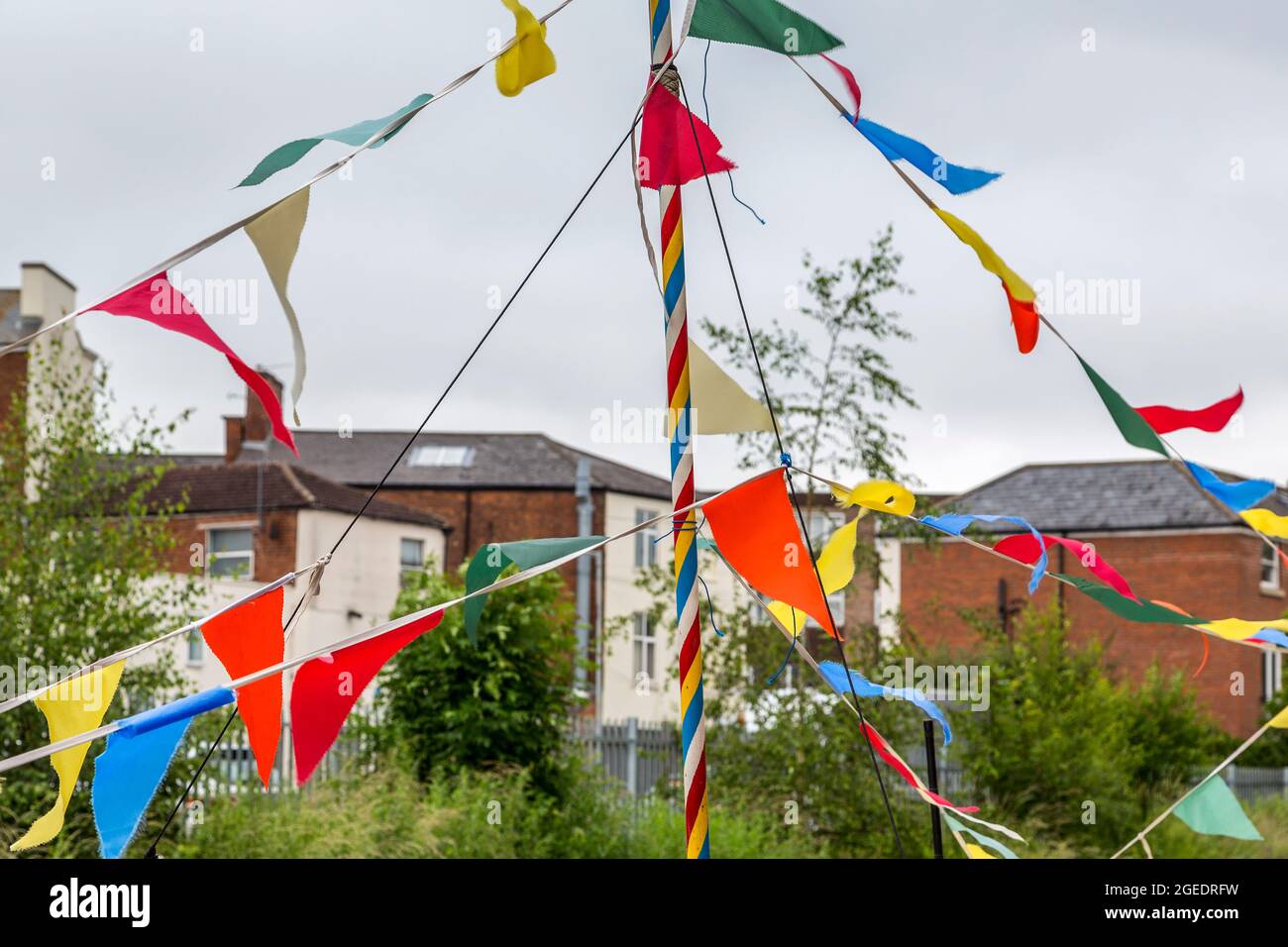 A brightly coloured flagpole and triangular flags contrast with the subdued colours of the dull urban landscape beyond. Stock Photo