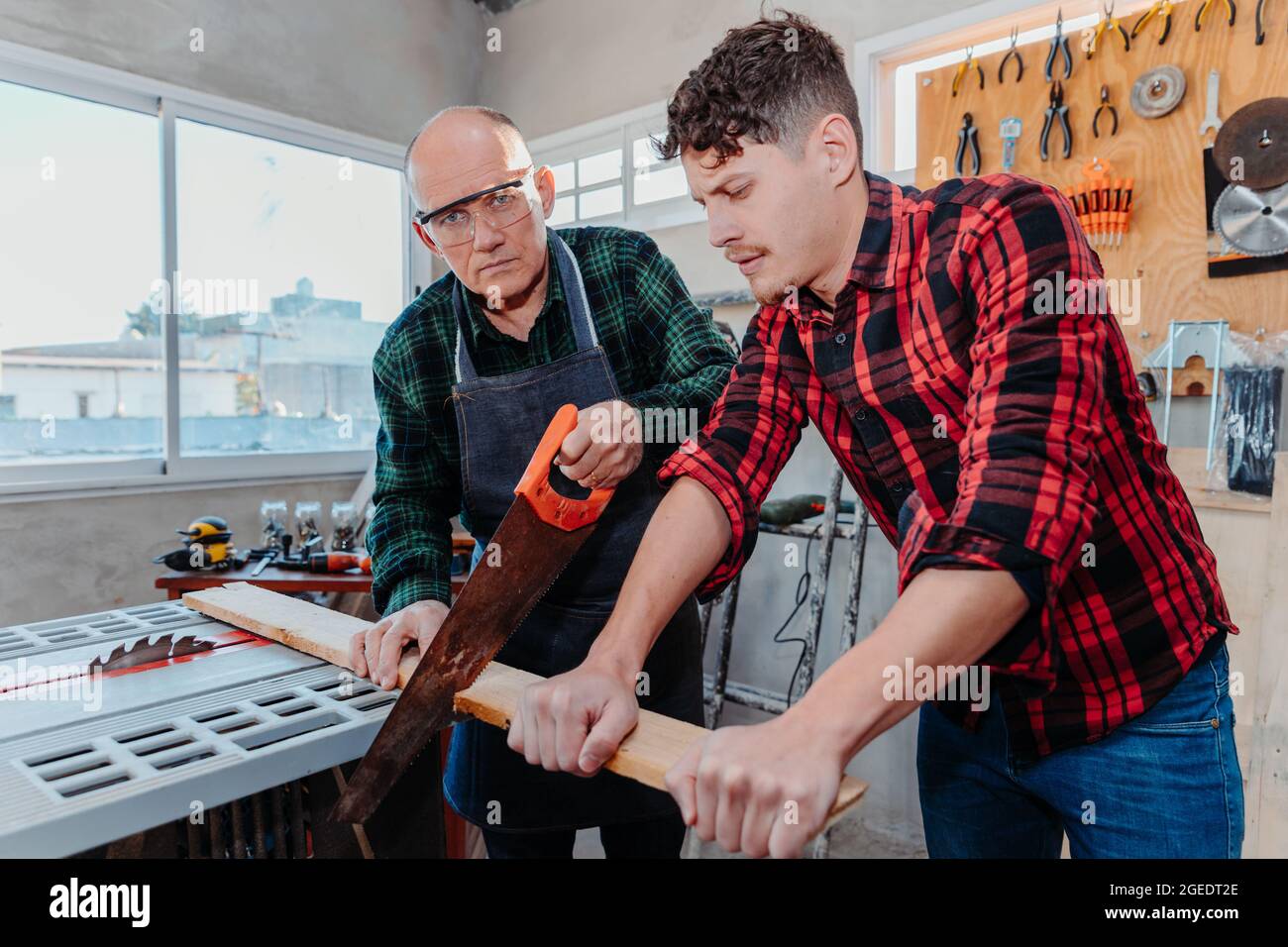 Senior carpenter teaching a younger man how to work Stock Photo