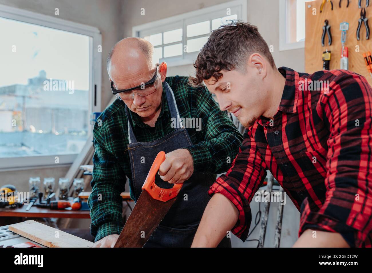 Senior carpenter teaching a younger man how to work Stock Photo