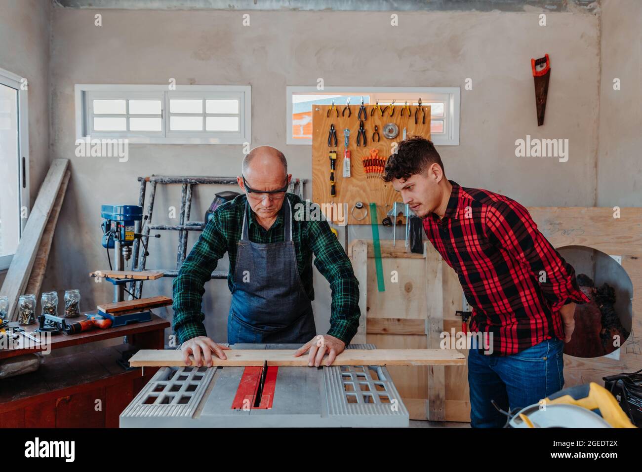 Senior carpenter teaching a younger man how to work Stock Photo