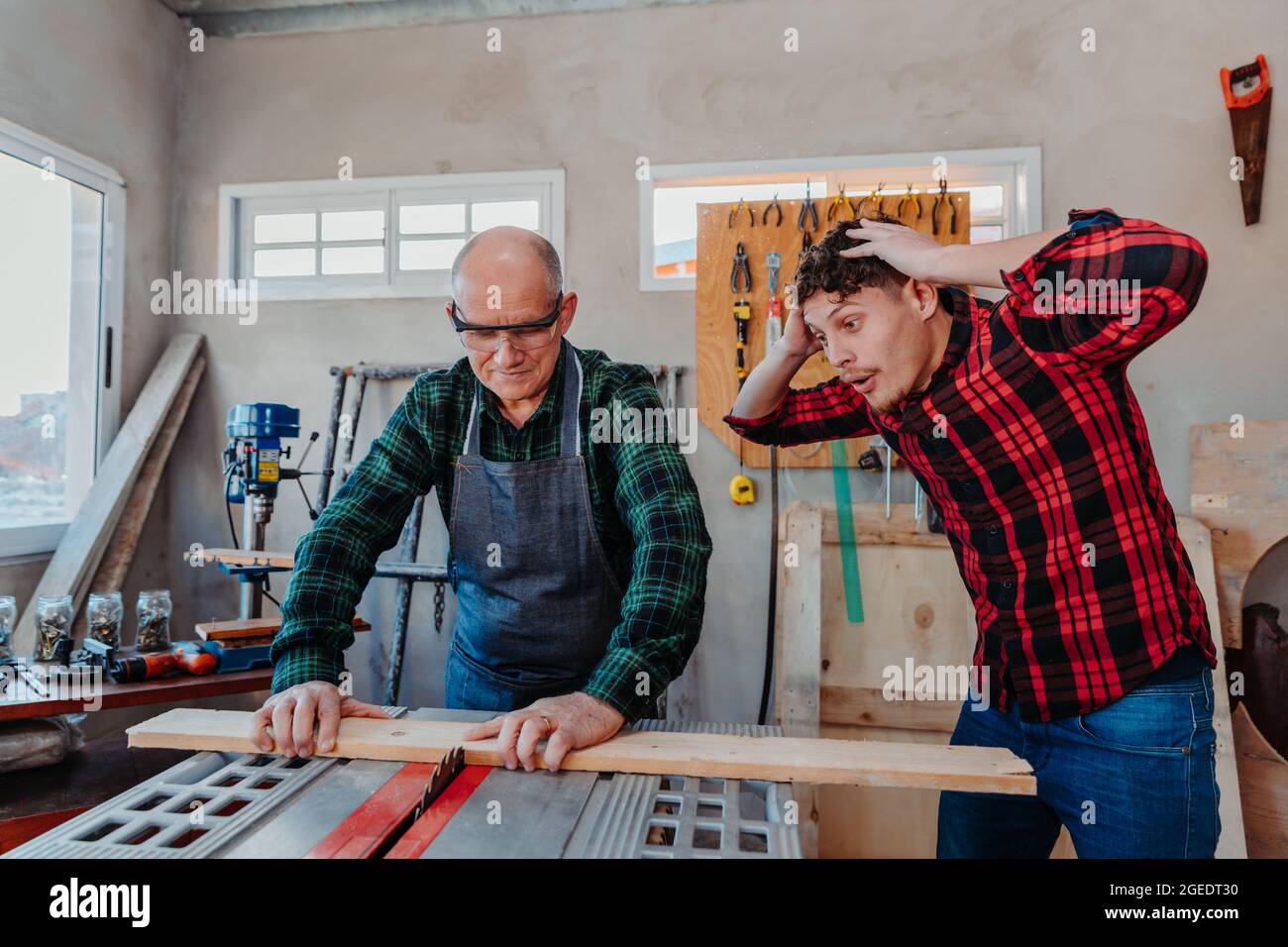 Senior carpenter teaching a younger man how to work Stock Photo
