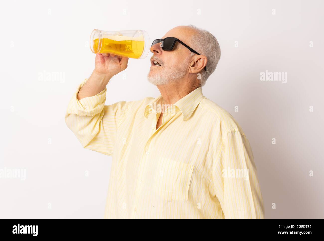 Old man with sunglasses drinking beer isolated over white background. Stock Photo