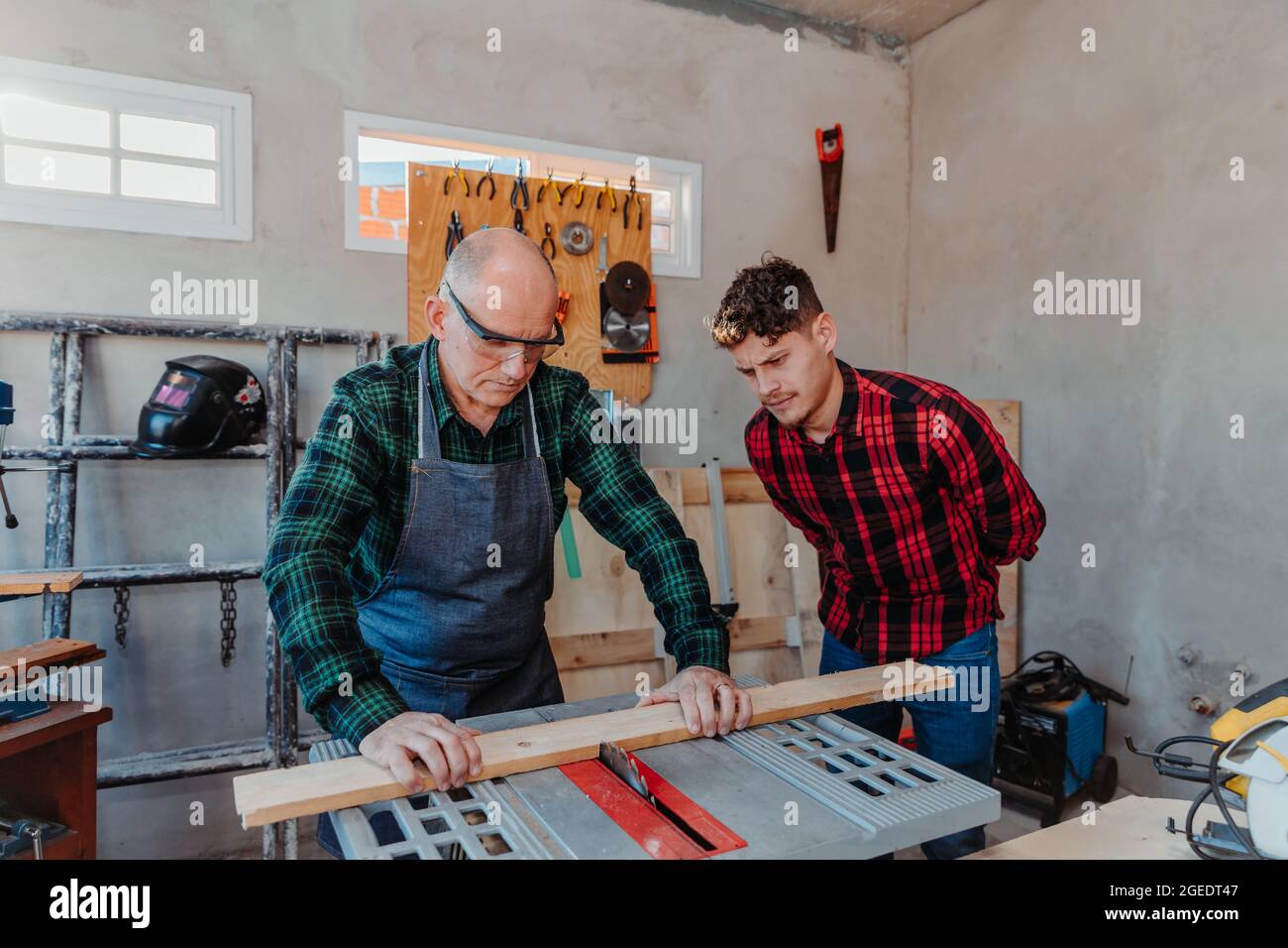 Senior carpenter teaching a younger man how to work Stock Photo