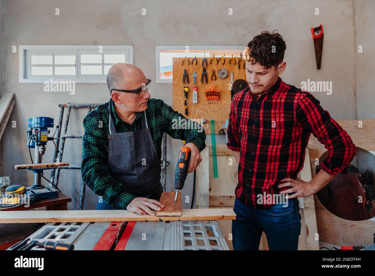 Senior carpenter teaching a younger man how to work Stock Photo