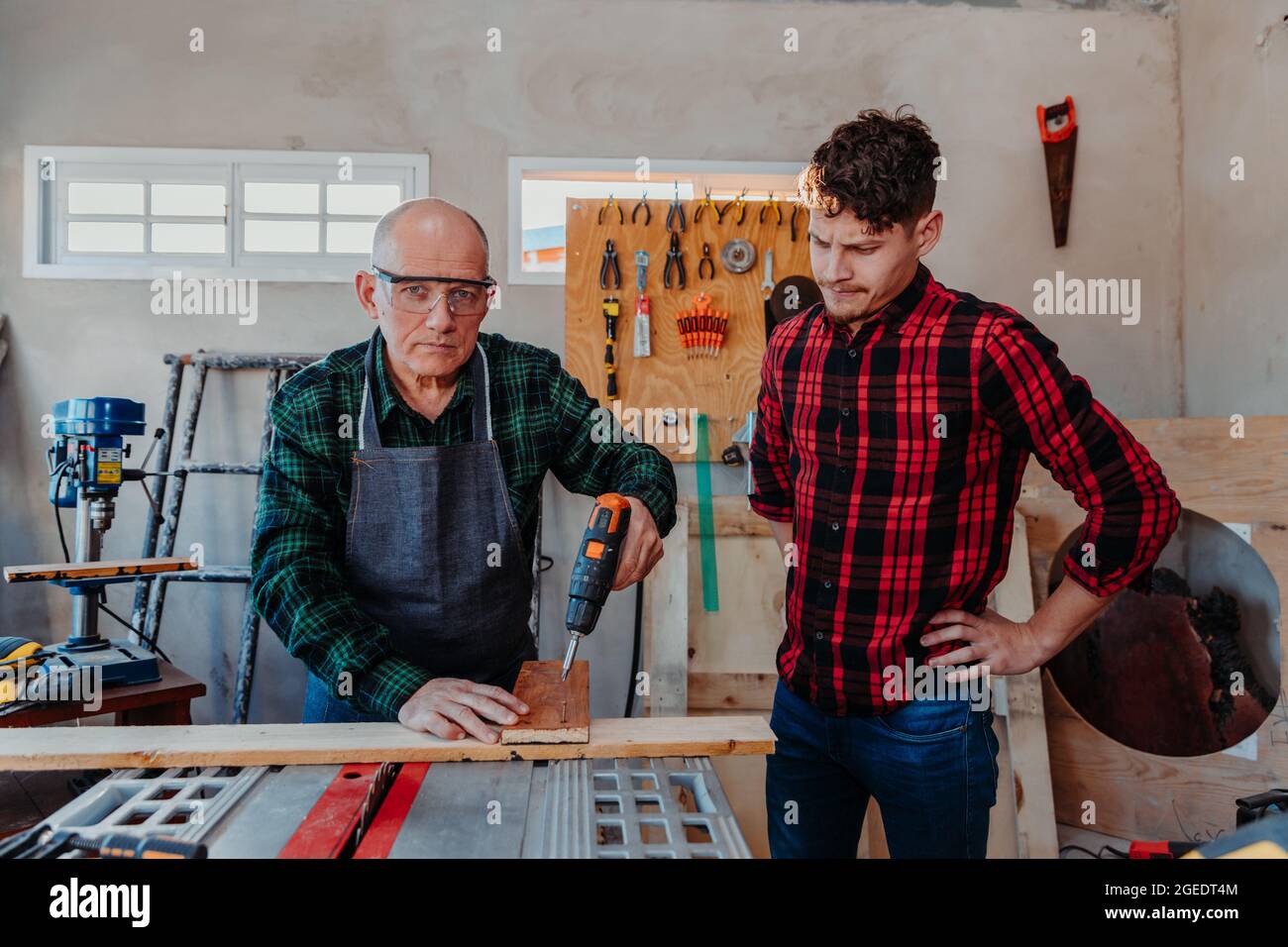 Senior carpenter teaching a younger man how to work Stock Photo