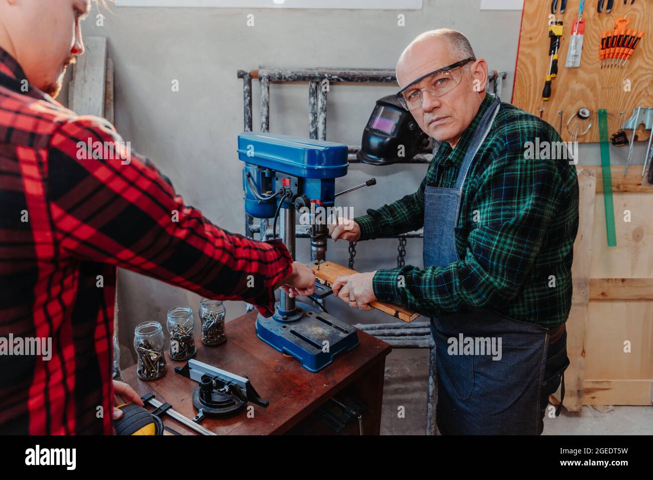 Senior carpenter teaching a younger man how to work Stock Photo