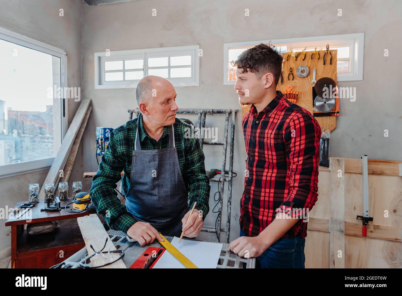 Senior carpenter teaching a younger man how to work Stock Photo