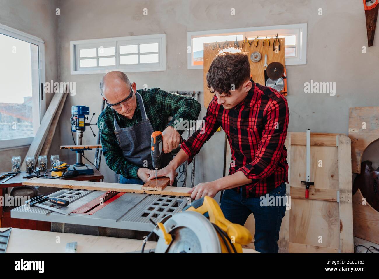 Senior carpenter teaching a younger man how to work Stock Photo