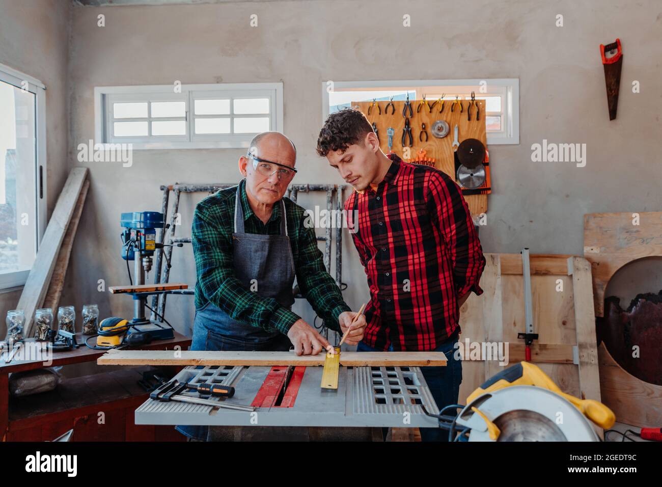 Senior carpenter teaching a younger man how to work Stock Photo