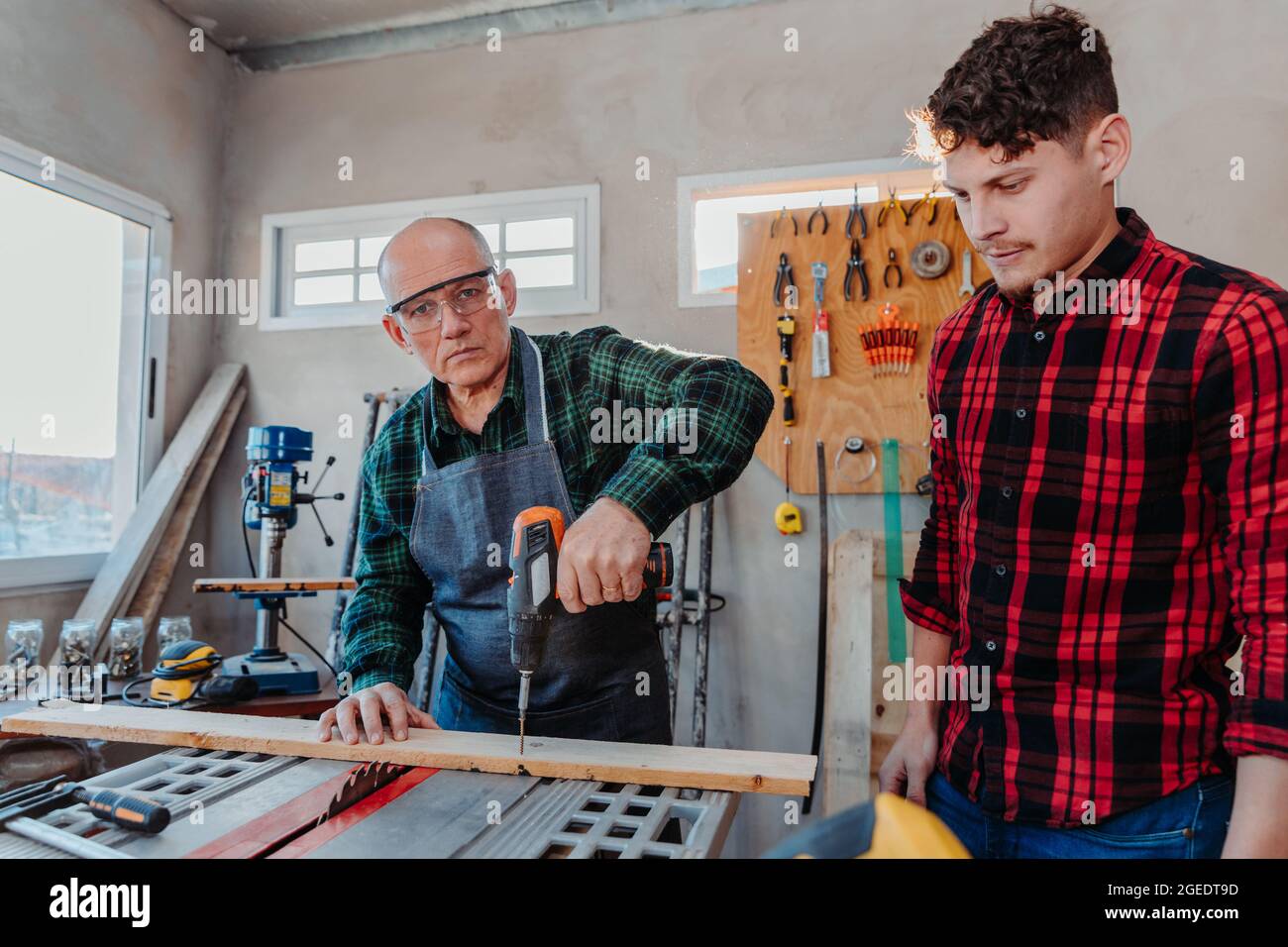 Senior carpenter teaching a younger man how to work Stock Photo