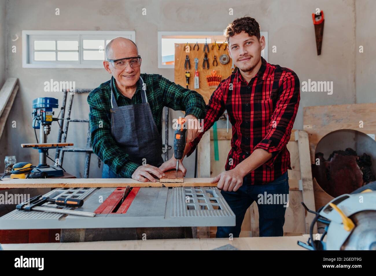 Senior carpenter teaching a younger man how to work Stock Photo