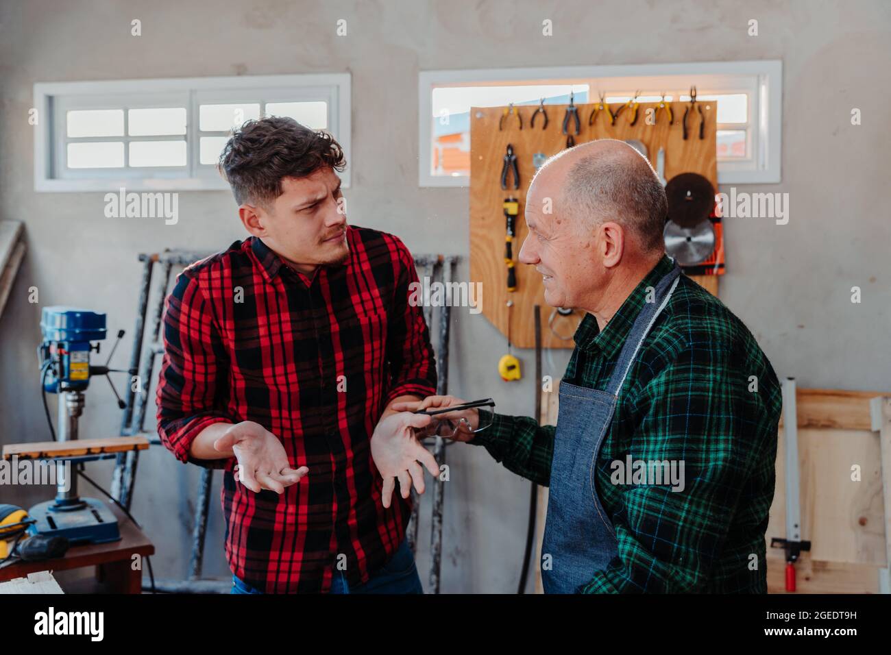 Senior carpenter teaching a younger man how to work Stock Photo