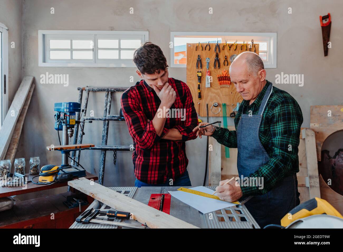 Senior carpenter teaching a younger man how to work Stock Photo